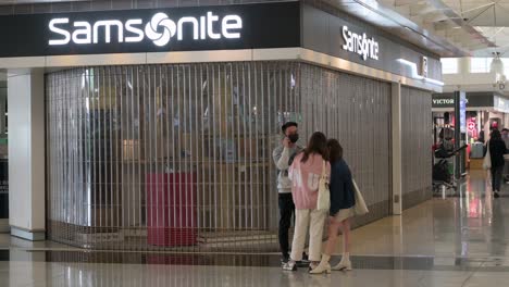 Passengers-walk-past-a-closed-American-luggage-manufacturer-and-retailer,-Samsonite-store-in-Hong-Kong-International-Airport-as-most-businesses-are-shutdown-due-to-the-Covid-19-variant-spread