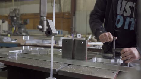 Hombre-Sujeta-Aluminio-A-Una-Mesa-De-Sierra-De-Cinta,-Proceso-De-Fabricación-De-Metal