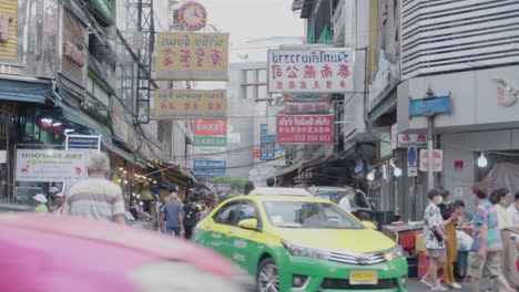 Tuk-Tuk,-Taxi-and-People-passing-by-in-busy-Street-at-Yaowarat-Chinatown-Bangkok
