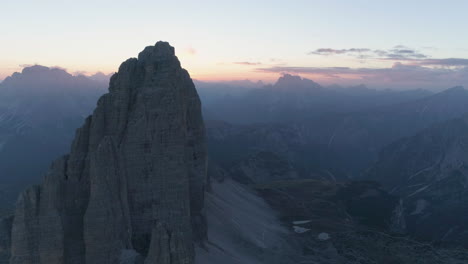Aerial-view-stunning-golden-sunrise-disappearing-behind-sharp-Tre-Cime-mountain-summit