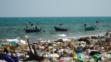 Traditional-Boats-With-Flag-Floating-In-The-Sea-With-Garbage-On-The-Beach