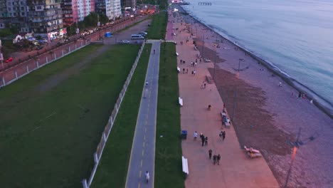 Flying-Above-Seaside-City-Promenade-At-Evening-Dawn