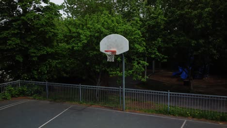 Basketballnetz-Mit-Grünen-Bäumen-Im-Hintergrund,-Luftaufnahme,-Dolly-Aus