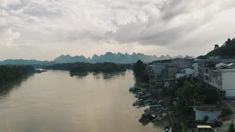 Flooded-River-on-Overcast-Day-in-China,-Karst-Mountains-in-Background