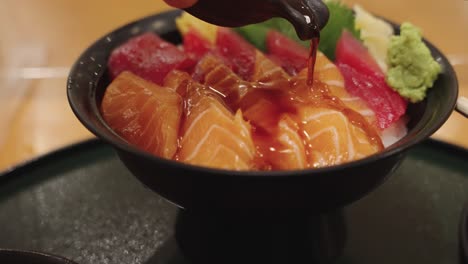 Tazón-De-Arroz-Sashimi-Japonés-Con-Salmón-Y-Atún,-Chef-Vertiendo-Salsa