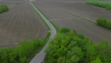 Landwirtschaftlicher-Traktor,-Der-Auf-Der-Straße-Zwischen-Dem-Leeren-Ländlichen-Feld-Fährt