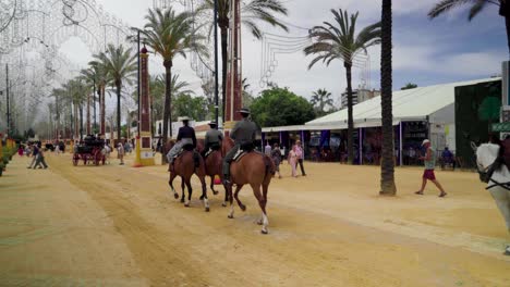 Women-and-men-ride-horses-in-jinete-and-flamenco-outfits-at-fair-in-Jerez,-Spain