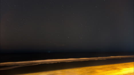 Timelapse-of-a-beautiful-stars-rotating-across-the-night-sky-above-a-scenic-beach