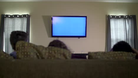 Blauer-Fernseher-Mit-Drei-Hinterköpfen,-Die-Auf-Der-Couch-Sitzen-Und-Zusehen