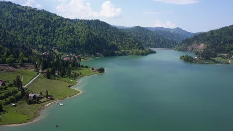 Aerial-Slow-Panning-shot-of-Lake-with-clear-water-and-trees-in-the-background-in-the-valley