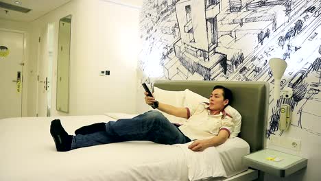 asian-man-relax-at-hotel-room-and-watching-tv-till-sleepy