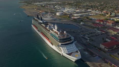 Aerial-overview-of-the-big-cruise-ship-in-dock-with-small-ships-sailing-in-the-marina-4K