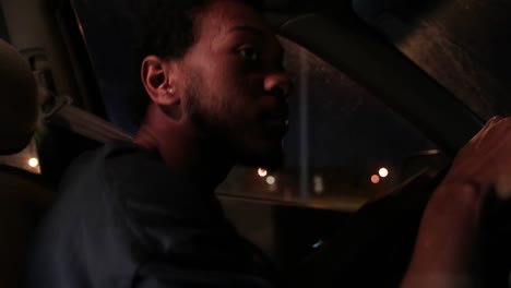 Young-African-American-black-man-drives-car-at-night-close-up