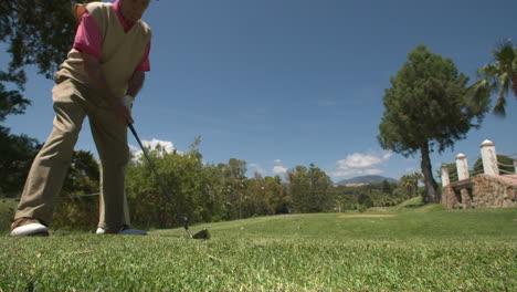 Senior-male-golfer-teeing-off-in-super-slow-motion-on-a-sunny-day-at-a-golf-course-in-Marbella,-Spain