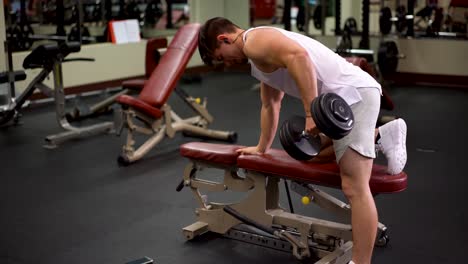 Rear-side-shot-of-young-bodybuilder-doing-one-arm-dumbbell-rows-using-a-bench