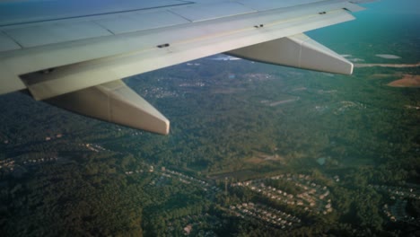 the-view-from-behind-an-ariplane-wing-as-it-flies-over-a-forested-area