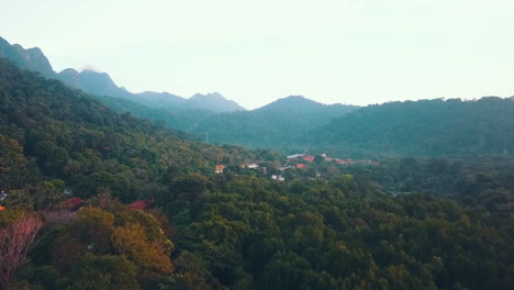 Revealing-shot-of-a-village-in-the-middle-of-a-rainforest-with-the-mountains-in-the-background,-Langkawi,-Malaysia