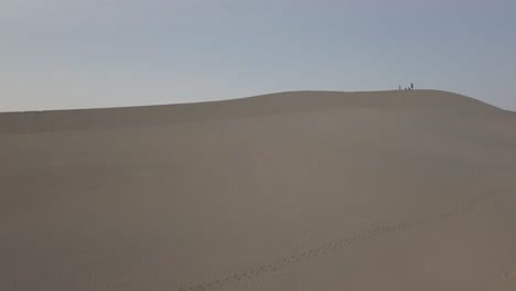 Luftdrohnenaufnahme-Einer-Gruppe-Von-Menschen,-Die-Auf-Einer-Sanddüne-Im-Death-Valley-Spazieren-Gehen