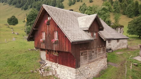 romantic-wooden-farm-house-in-the-swiss-moutains,-aerial-drone-flight