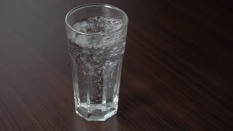 Stilles-Wasser-In-Ein-Hohes-Glas-Auf-Einem-Holztisch-Gießen