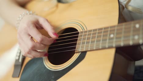 Close-up-view-of-woman's-hand-with-red-manicure-playing-the-classic-acoustic-guitar