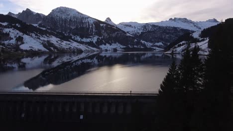 Gran-Panorama-De-Montaña-De-Invierno-En-Un-Lago-Artificial-Con-Un-Tipo-En-La-Presa-En-Suiza