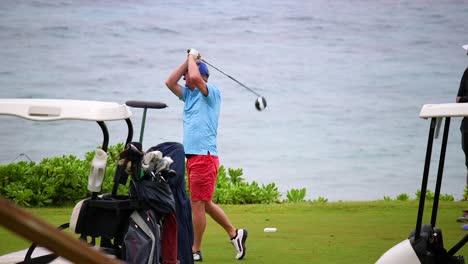 Slow-motion-shot-of-caucasian-male-golfer-hitting-a-golf-ball-on-a-course-by-the-ocean-in-Curacao,-Caribbean