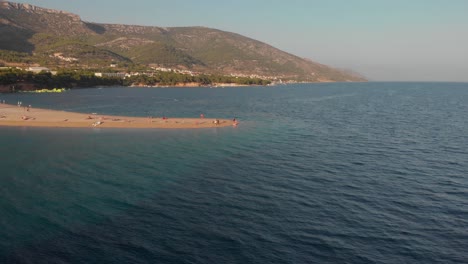 Slowly-flying-toward-the-very-end-of-the-famous-Zlatni-Rat-beach-on-the-island-of-Brac-in-Croatia,-revealing-tourists-and-beachgoers