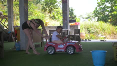Woman-playing-with-little-boy-in-a-pink-toy-car