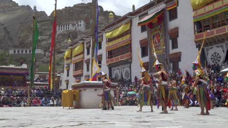 Masked-monks-dressed-in-colorful-dresses-dance-in-monastery-in-front-of-tourists-at-daytime
