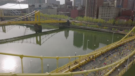 Slow-aerial-passing-over-runners-crossing-bridge,-Pittsburgh-Marathon