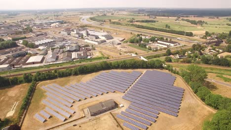 A-smooth-high-angle-aerial-shot-revealing-a-solar-farm-below-with-industry-and-active-waterways-transporting-goods