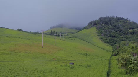 Powerlines-on-a-lush,-rolling-green-hill-landscape-on-the-Hawaiian-island,-Maui