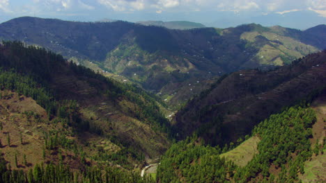 Drone-Sobre-El-Bosque-De-Montaña-Hasta-El-Valle-En-La-Montaña,-Mostrando-Caminos-Y-Casas-En-Las-Montañas