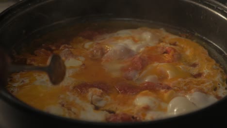 Refugees-cooking-dish-with-eggs-and-spices-in-pan-inside-tent