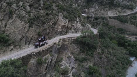 Aerial-drone-shot-of-a-Willis-Jeep-with-tourist-in-a-narrow-road-in-Real-de-Catorce,-San-Luis-Potosi,-Mexico