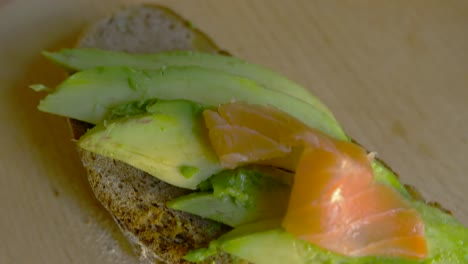 Top-view-of-female-putting-salmon-on-avocado-toast
