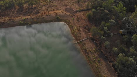 Overview-drone-shot-of-a-damlake-in-the-outback-in-Australia-With-reflections-in-the-water-and-pipeline