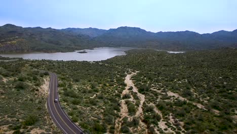 Aerial-pull-back-down-wash-from-Bartlett-Lake-to-desert-with-a-good-view-of-the-traffic-on-the-Bartlett-Damn-Road,-Tonto-National-Forest,-Scottsdale,-Arizona