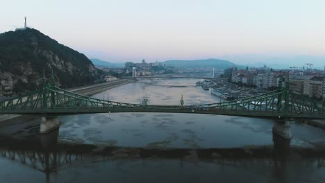 Aerial-view-of-Tram-passing-through-Liberty-bridge-on-river-Danube-in-Budapest-at-sunrise,-morning