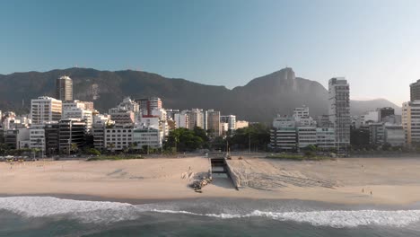 Slow-aerial-panning-down-of-the-skyline-of-Rio-de-Janeiro-at-sunrise-with-the-Corcovado-mountain-and-canal-leading-from-the-city-lake-to-the-beach-of-Leblon-seen-from-above-the-ocean