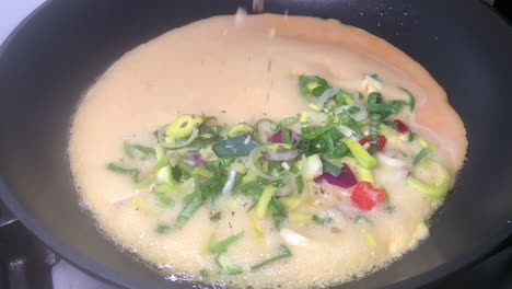 Extreme-slow-motion-shot-of-oregano-and-basil-herbs-from-Italian-mix-sprinkle-over-Spanish-vegetable-omelet-in-frying-pan