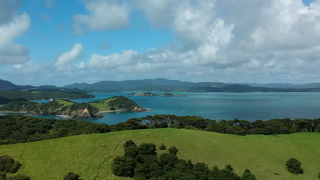 Aerial-view-of-scenic-Bay-of-Islands-aera,-New-Zealand,-Drone-revealing-shot-of-lush-hills-with-palm-trees-and-the-blue-ocean-in-the-background