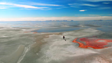 Aerial-of-a-young-girl-walking-on-a-desolate-landscape-by-the-great-salt-lake