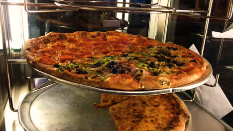 Köstliche-Italienische-Pizza,-Die-Sich-In-Einem-Glasdisplay-Dreht,-Heiß-Und-Essfertig