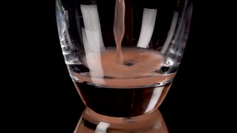 Pouring-in-grapefruit-juice-in-a-beautiful-glas-in-slow-motion-in-front-of-a-black-background