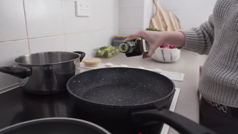 Woman-hands-pouring-olive-oil-into-frying-pan-before-cooking