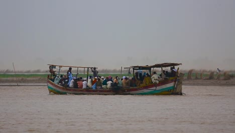 Huge-group-of-Asian-Pakistani-people-with-ladies-and-motor-bikes-travelling-on-boat-over-a-river,-People-under-the-shelter-of-the-boat