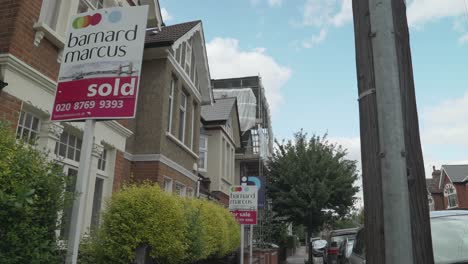 A-slow-pan-of-a-Barnard-Marcus-Sold-and-For-Sale-Estate-Agent-Board-on-a-Residential-Street-in-South-West-London