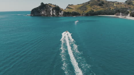 AERIAL:-Following-boat-over-water-at-Hahei-Beach